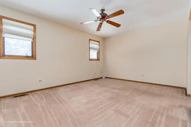 an empty room with a window and a ceiling fan