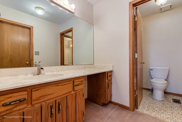 a bathroom with a granite countertop sink mirror and toilet