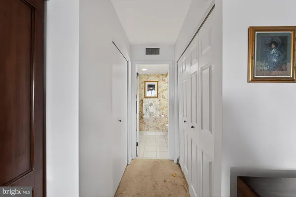a view of a hallway with wooden floor and a bathroom