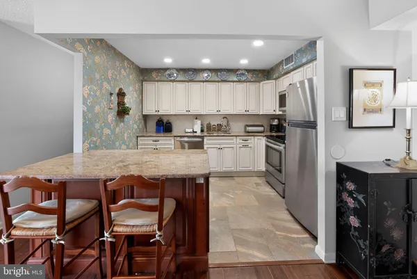a kitchen with stainless steel appliances granite countertop a table chairs sink and cabinets