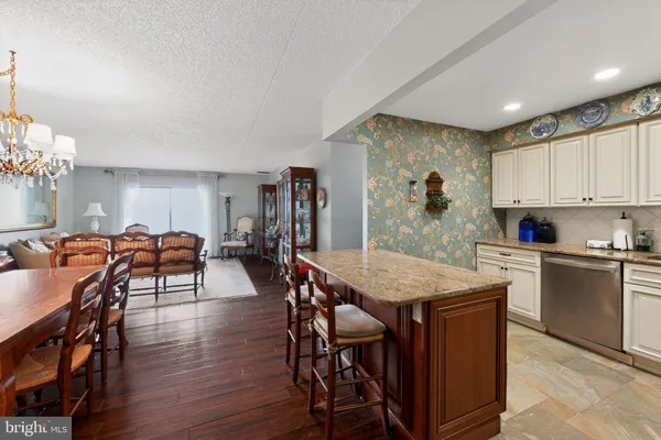 a open kitchen with stainless steel appliances granite countertop a stove a refrigerator a kitchen island a dining table and chairs with wooden floor