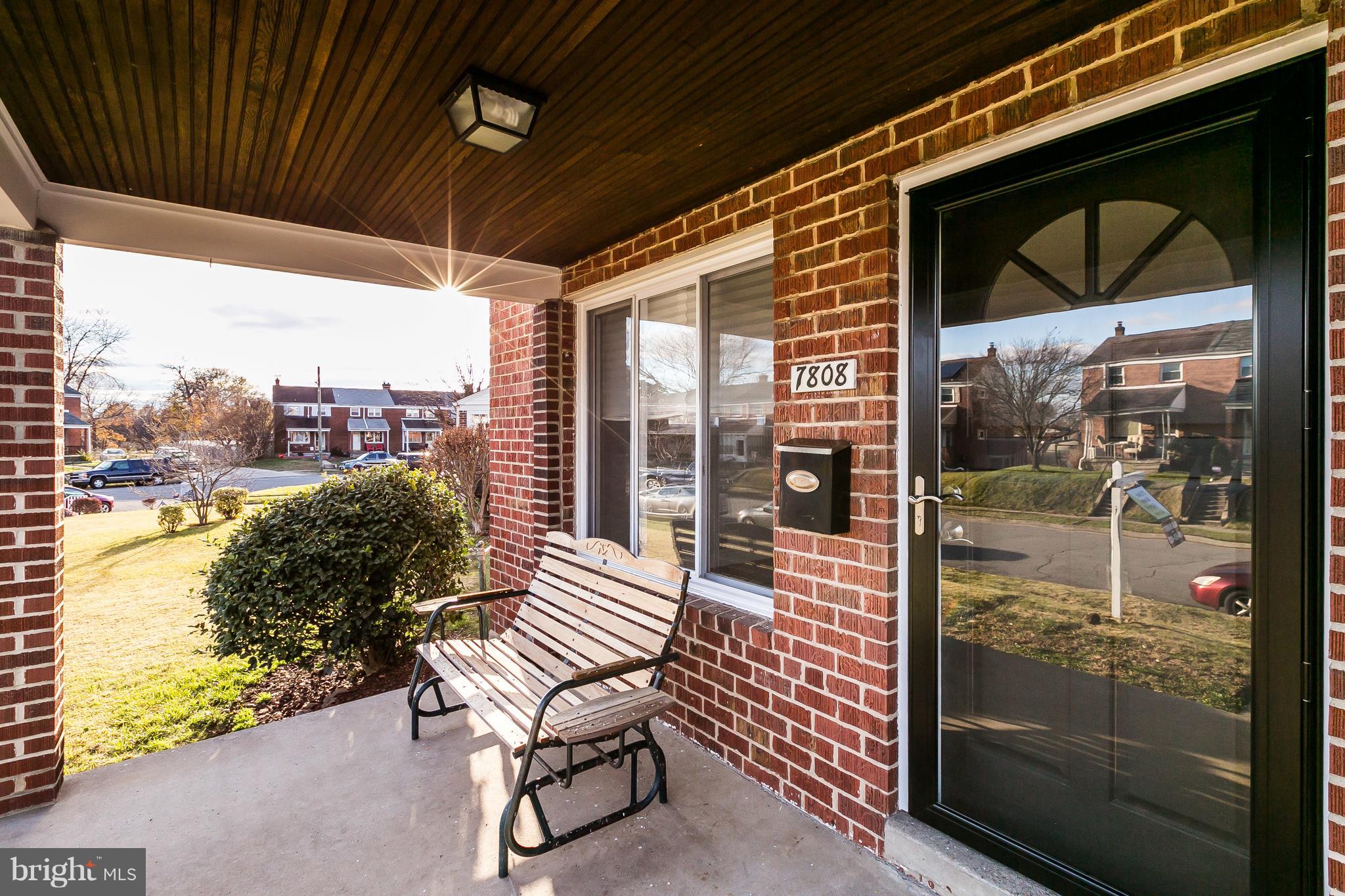 7808 Charlesmont Road Baltimore, MD 21222 - Photo 1 of 32 a porch with a bench next to a yard