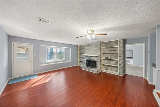 a view of an empty room with wooden floor and a fireplace