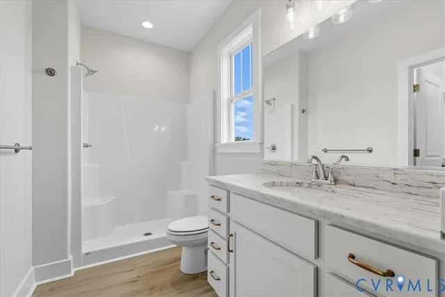 a bathroom with a granite countertop sink a toilet and shower