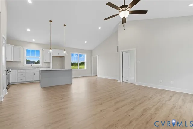 a view of kitchen with stainless steel appliances refrigerator wooden floor and a ceiling fan