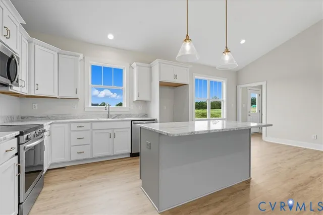 a kitchen with kitchen island granite countertop a stove a sink a center island and cabinets