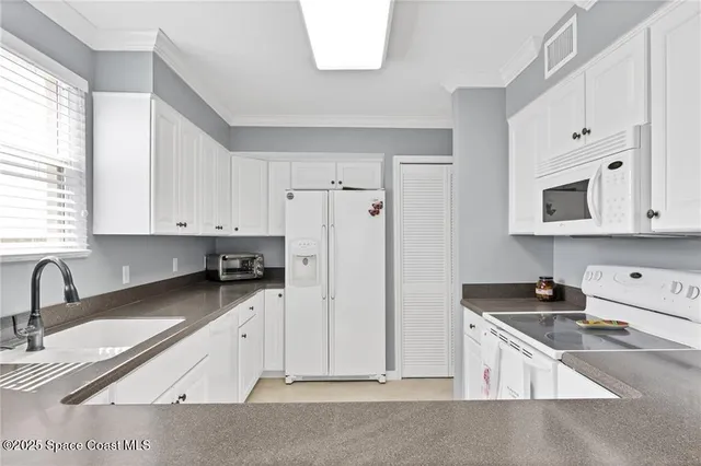 a kitchen with granite countertop a sink a stove a refrigerator a counter space and cabinets