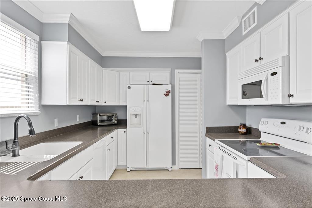 6061 North River Run Drive, Unit 6061 Sebastian, FL 32958 - Photo 20 of 36 a kitchen with granite countertop a sink a stove a refrigerator a counter space and cabinets