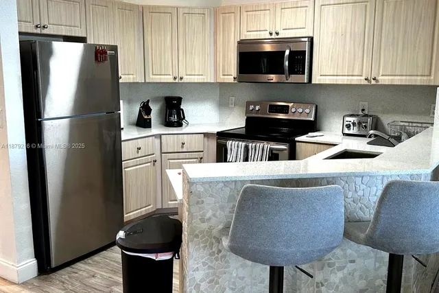 a kitchen with stainless steel appliances granite countertop a refrigerator a stove a sink and a microwave