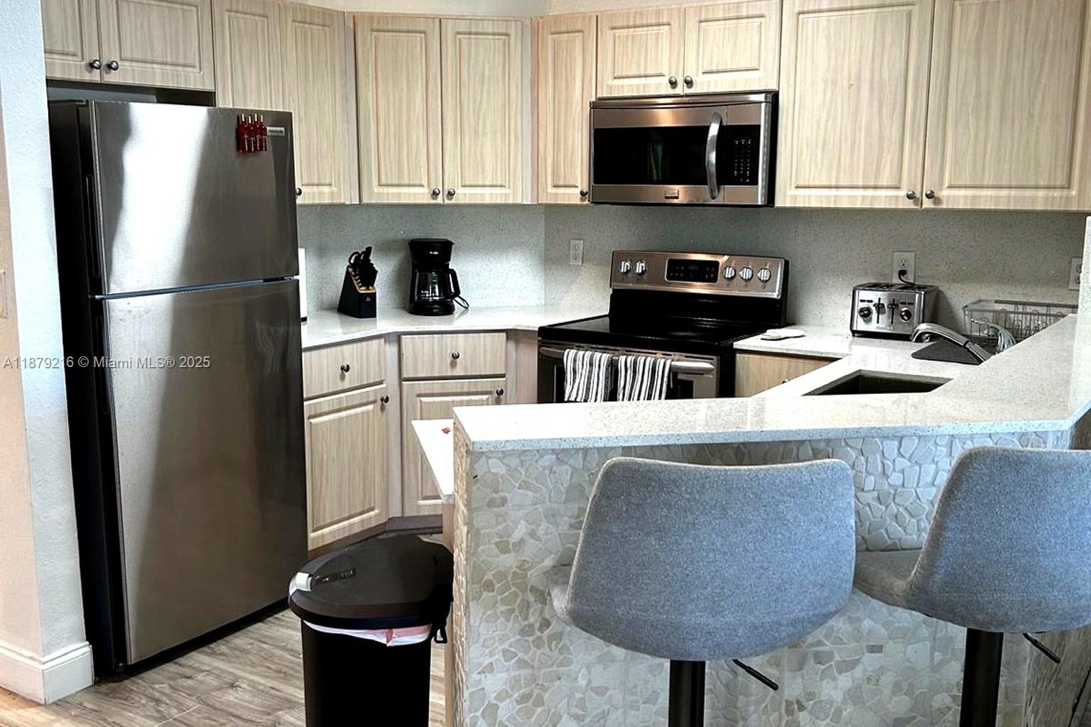 13221 Southwest 53rd Street Miramar, FL 33027 - Photo 12 of 24 a kitchen with stainless steel appliances granite countertop a refrigerator a stove a sink and a microwave