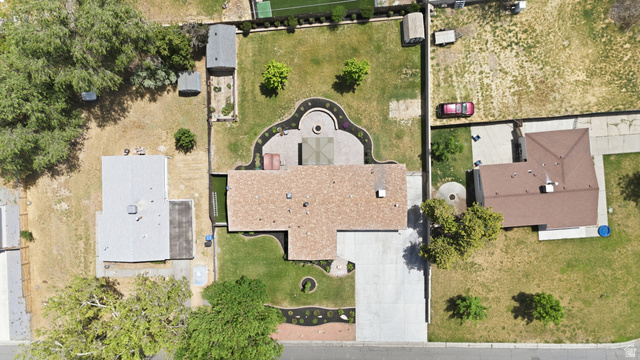 6889 South Village Road Salt Lake City, UT 84121 - Photo 42 of 44 Aerial view highlighting a residential property with a brown shingle roof, a concrete driveway, a structured backyard patio, a grass lawn, and surrounding landscaping