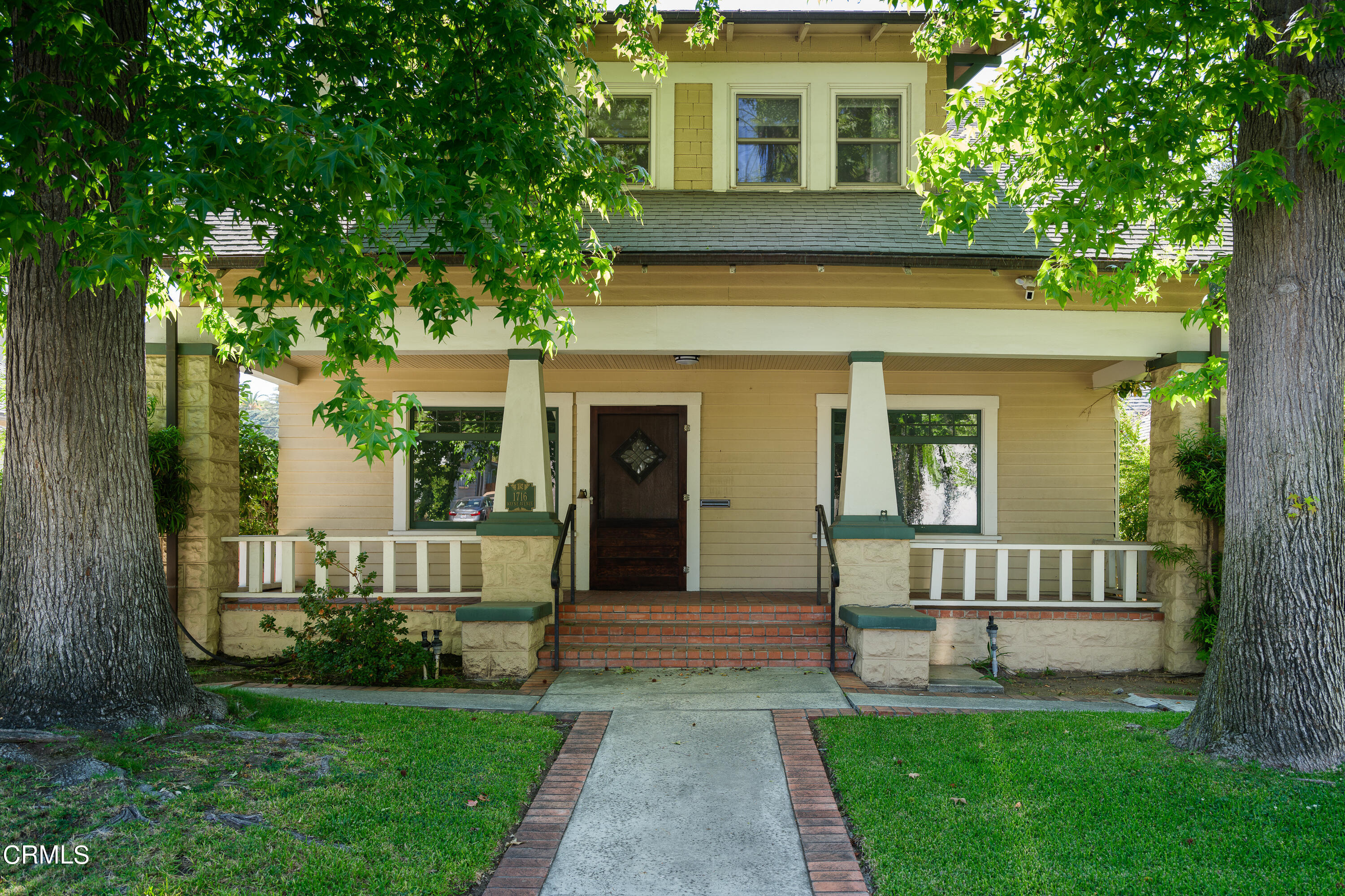 a view of a house with a yard and a large tree