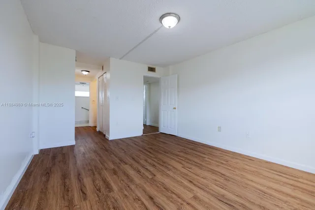 a view of an empty room with wooden floor