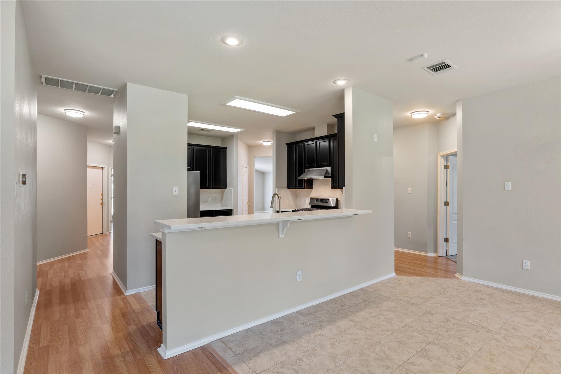 4725 Tello Path Austin, TX 78749 - Photo 15 of 34 An open concept living area transitions to a modern kitchen with dark cabinetry and stainless steel appliances.