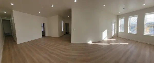 an empty room with wooden floor and windows