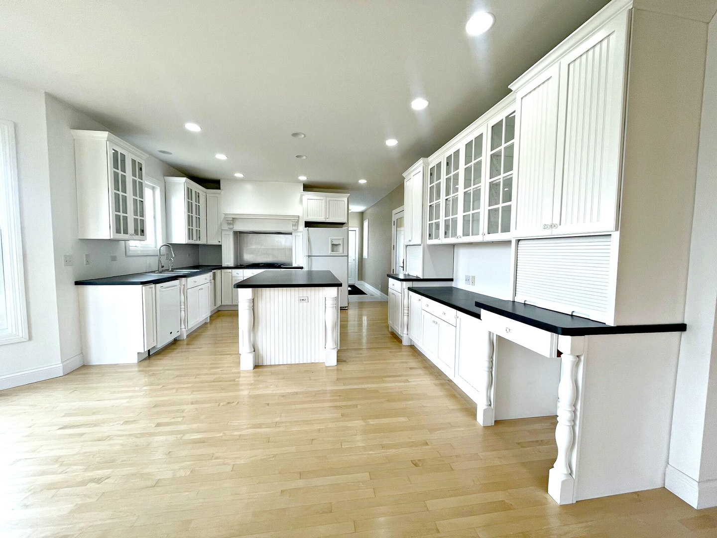 8208 Eagle Ridge Spring Grove, IL 60081 - Photo 9 of 39 a large white kitchen with wooden floor and a large window