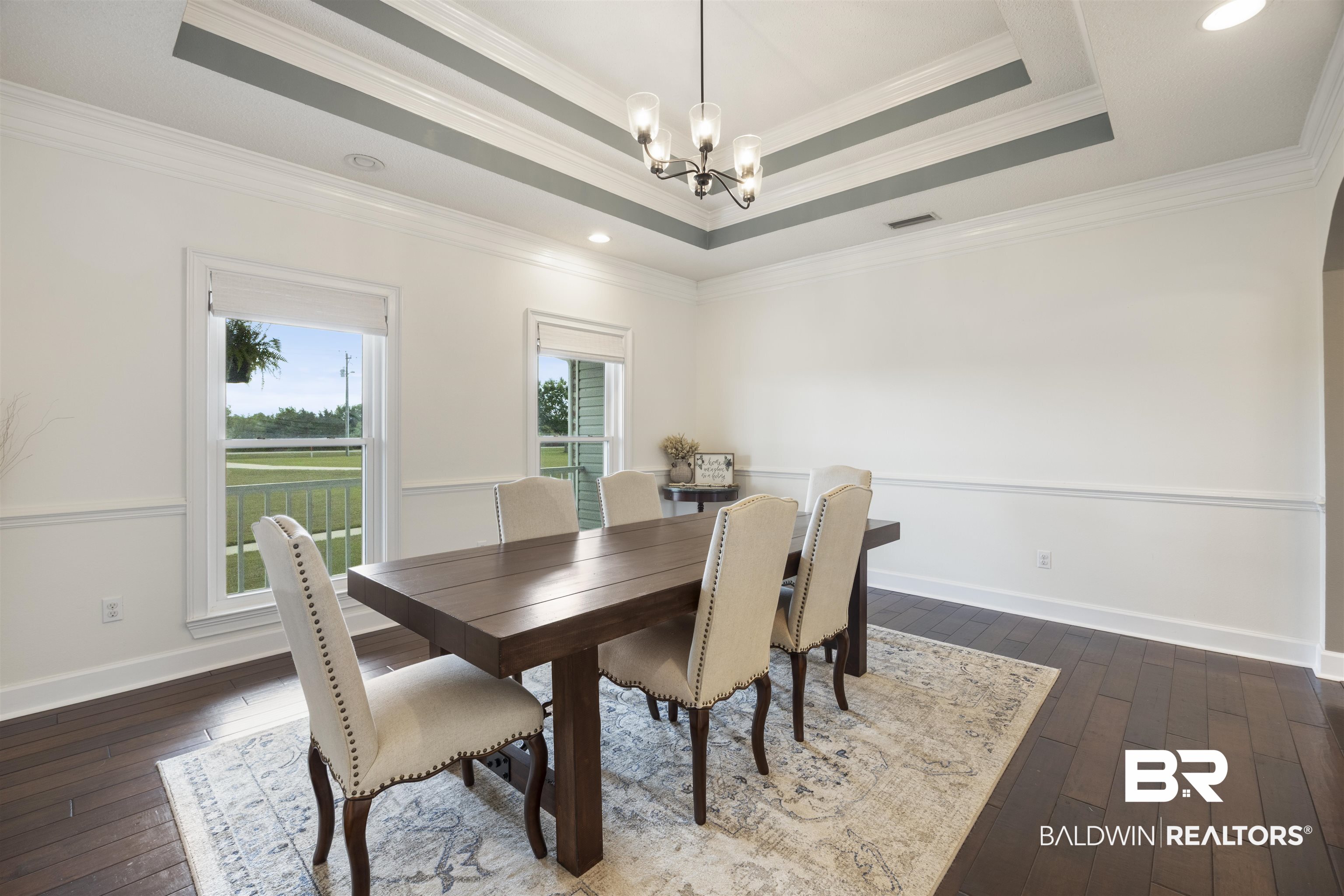 9855 Stucki Road Elberta, AL 36530 - Photo 11 of 54 Dining area with a chandelier, dark wood-style floors, crown molding, and a raised ceiling