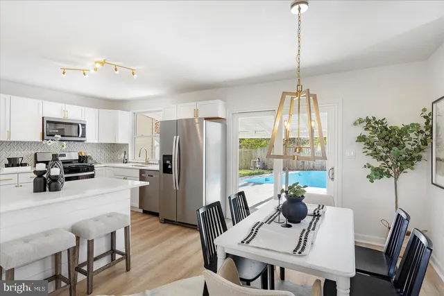 a kitchen with stainless steel appliances a dining table chairs a refrigerator a stove a dining table and a window