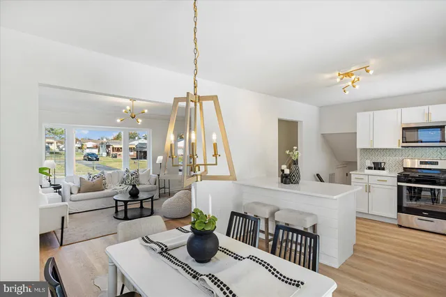 a kitchen with stainless steel appliances a dining table chairs a sink a rug a rug and a lamp