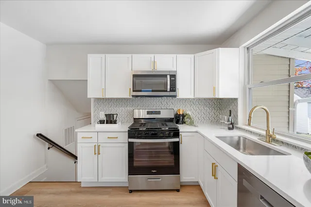 a kitchen with white cabinets a sink stove and microwave