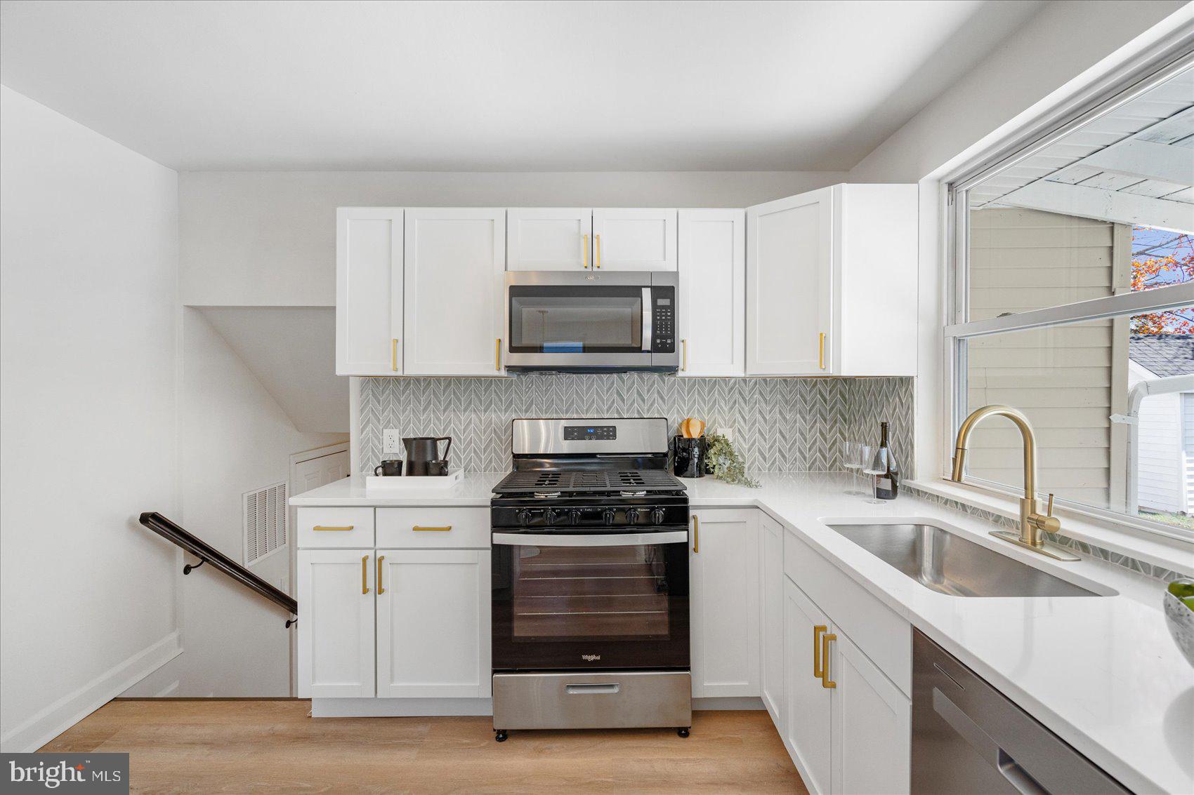 7803 Brevort Road Windsor Mill, MD 21244 - Photo 16 of 45 a kitchen with white cabinets a sink stove and microwave