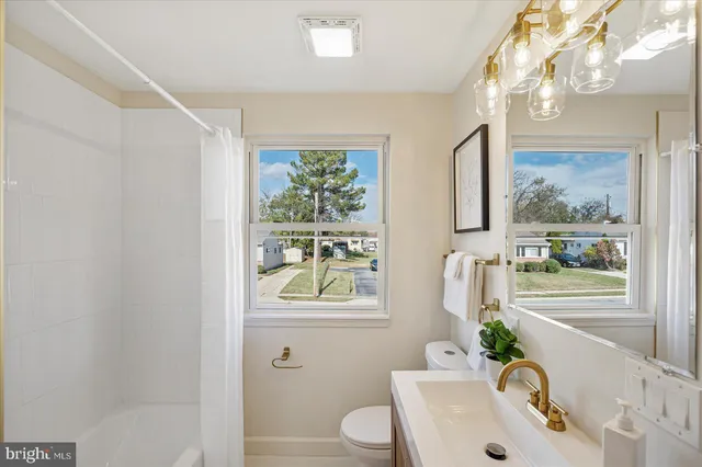 a bath room with a sink a toilet and a window