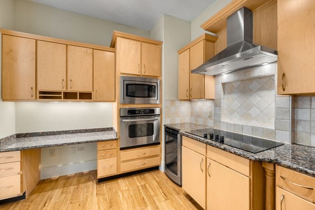 a kitchen with granite countertop wooden cabinets and a stove top oven