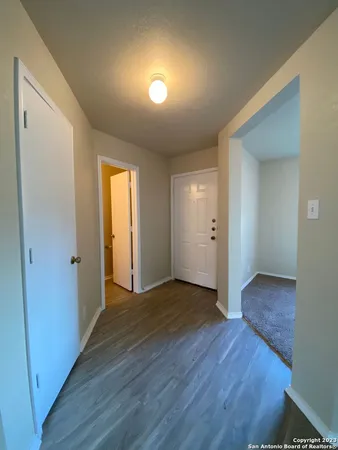 a view of an empty room with wooden floor and closet