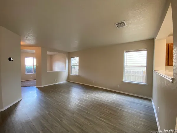 an empty room with wooden floor and windows