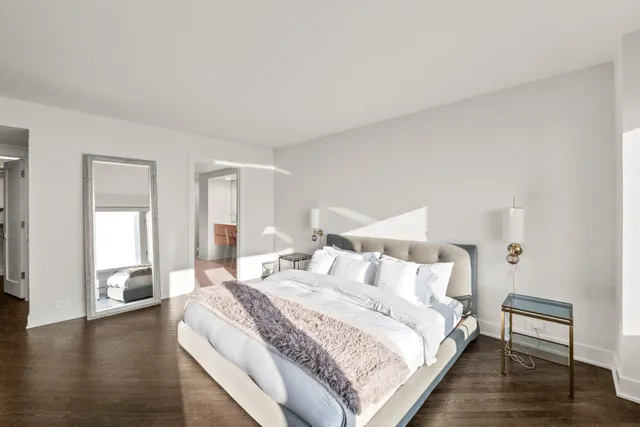 a spacious bedroom with a bed and wooden floor
