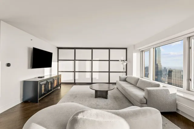 a living room with furniture a flat screen tv and a floor to ceiling window