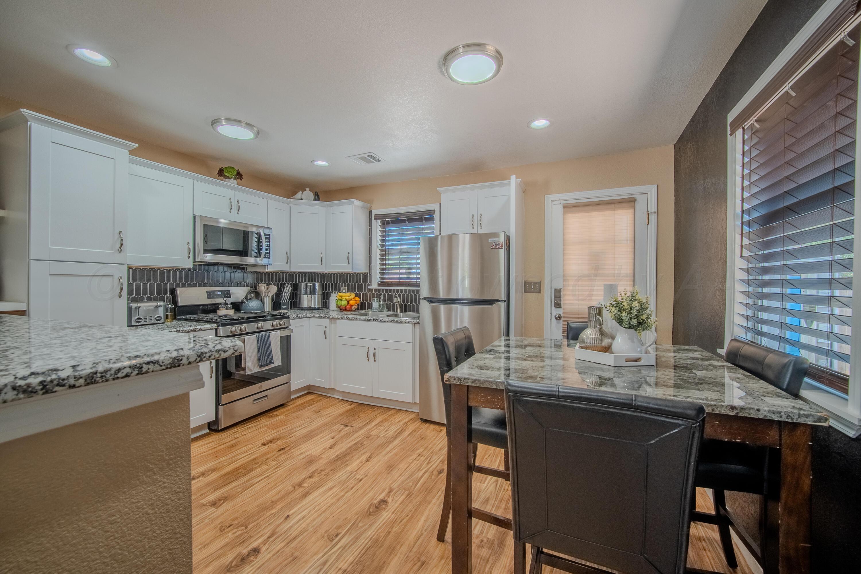 4014 Gables Street Amarillo, TX 79110 - Photo 3 of 14 a kitchen with stainless steel appliances granite countertop wooden cabinets a sink a stove a dining table and chairs