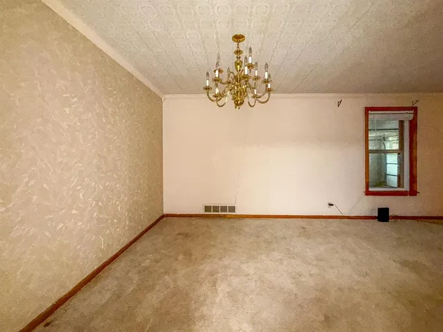 an empty room with chandelier fan and windows