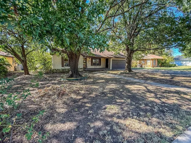 a backyard of a house with large trees and brick walls
