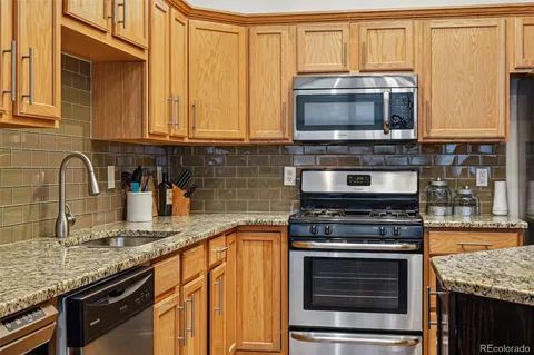 a kitchen with granite countertop a stove top oven microwave and cabinets
