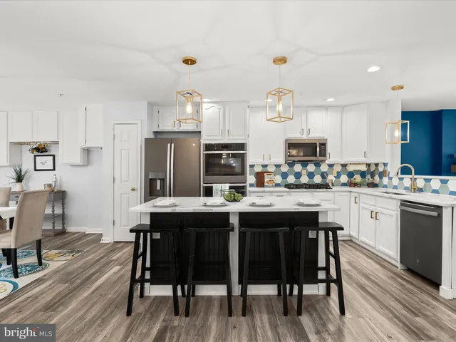 a kitchen with kitchen island granite countertop a table chairs sink and cabinets