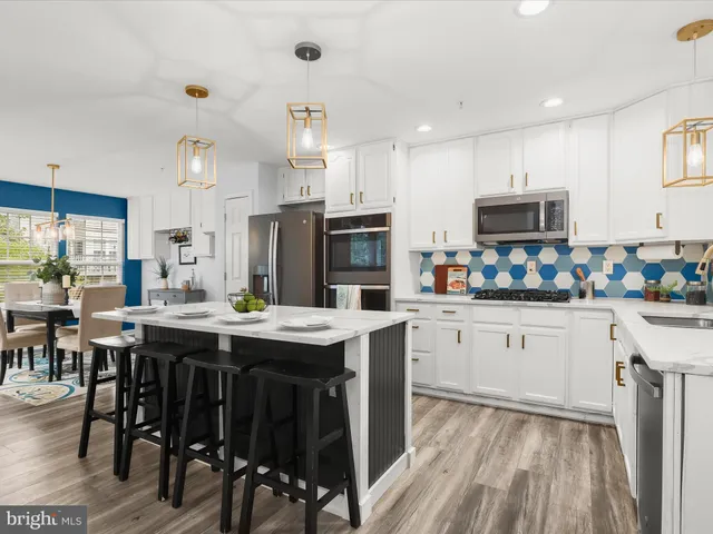 a kitchen with stainless steel appliances granite countertop a table chairs sink and cabinets