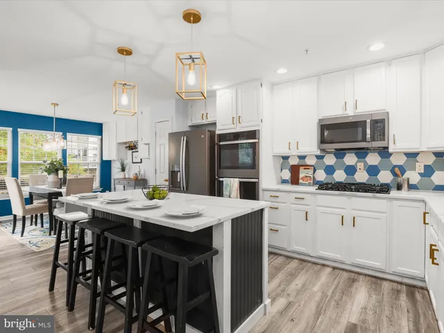 a kitchen with stainless steel appliances granite countertop a table chairs stove microwave and cabinets