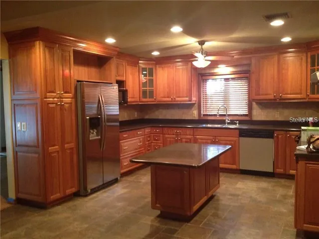 a kitchen with kitchen island granite countertop wooden cabinets and stainless steel appliances