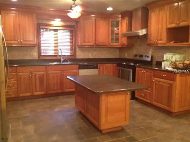 a kitchen with stainless steel appliances granite countertop a sink a stove and a refrigerator