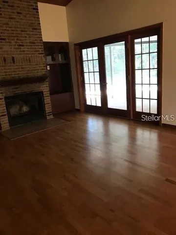 an empty room with wooden floor fireplace and windows