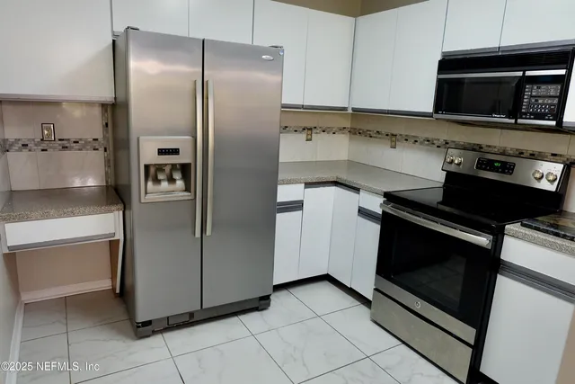 a kitchen with granite countertop a refrigerator and a stove