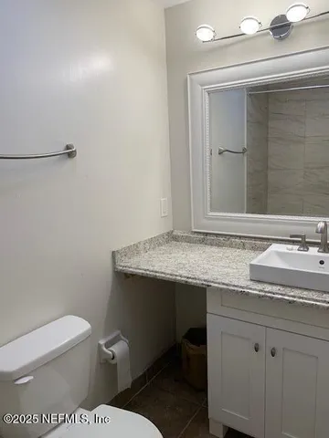 a bathroom with a granite countertop toilet sink and mirror