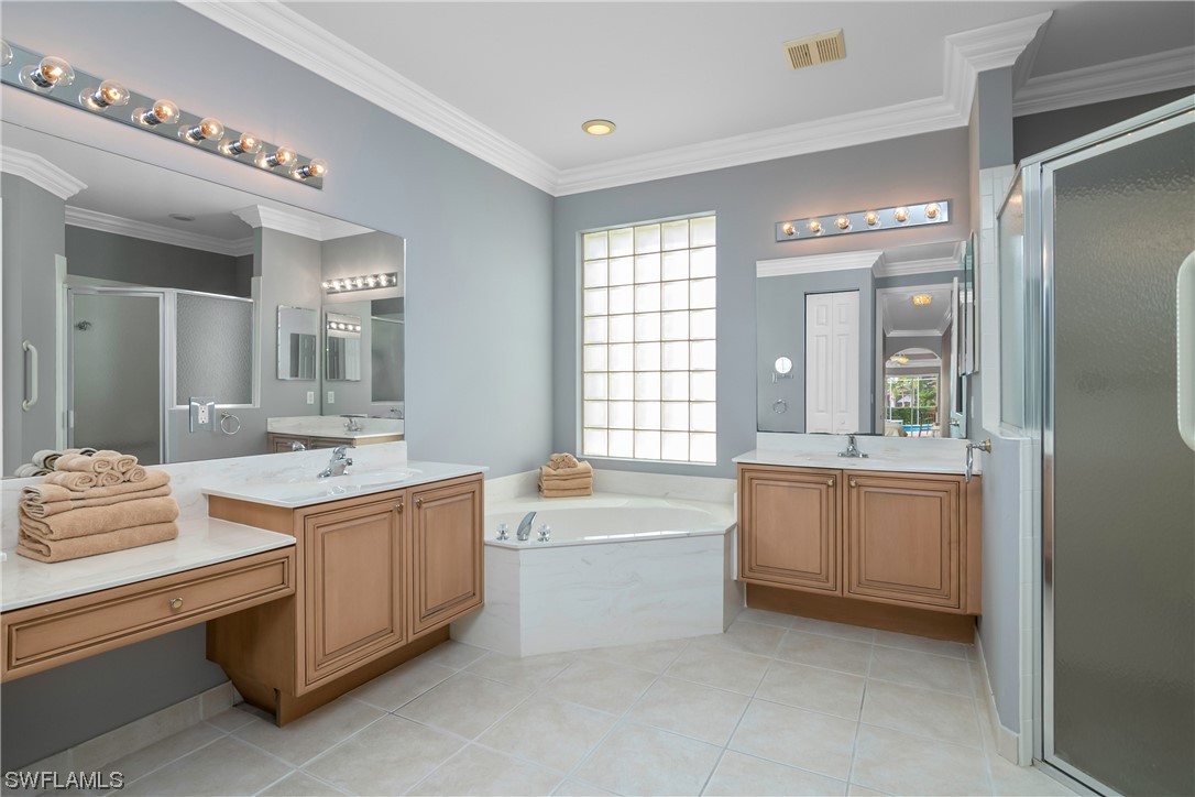 9057 Whitfield Drive Estero, FL 33928 - Photo 19 of 28 a bathroom with a tub double vanity sink and a large mirror