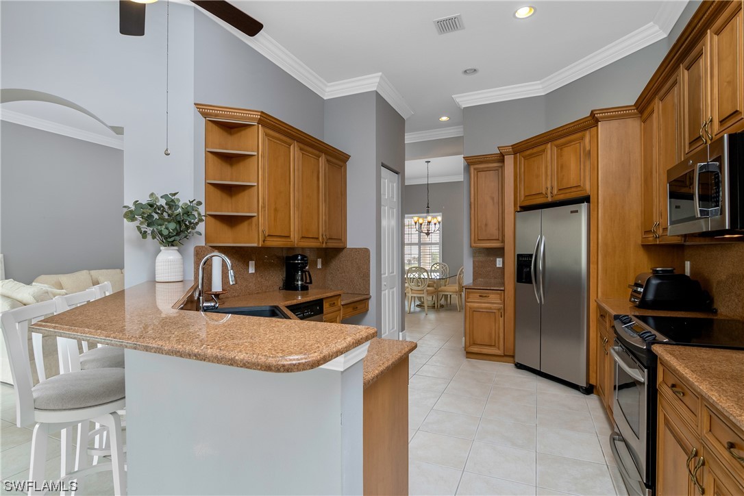 9057 Whitfield Drive Estero, FL 33928 - Photo 8 of 28 a kitchen with stainless steel appliances granite countertop a sink a refrigerator and a stove