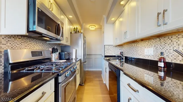 a kitchen with stainless steel appliances granite countertop a stove a sink and a microwave