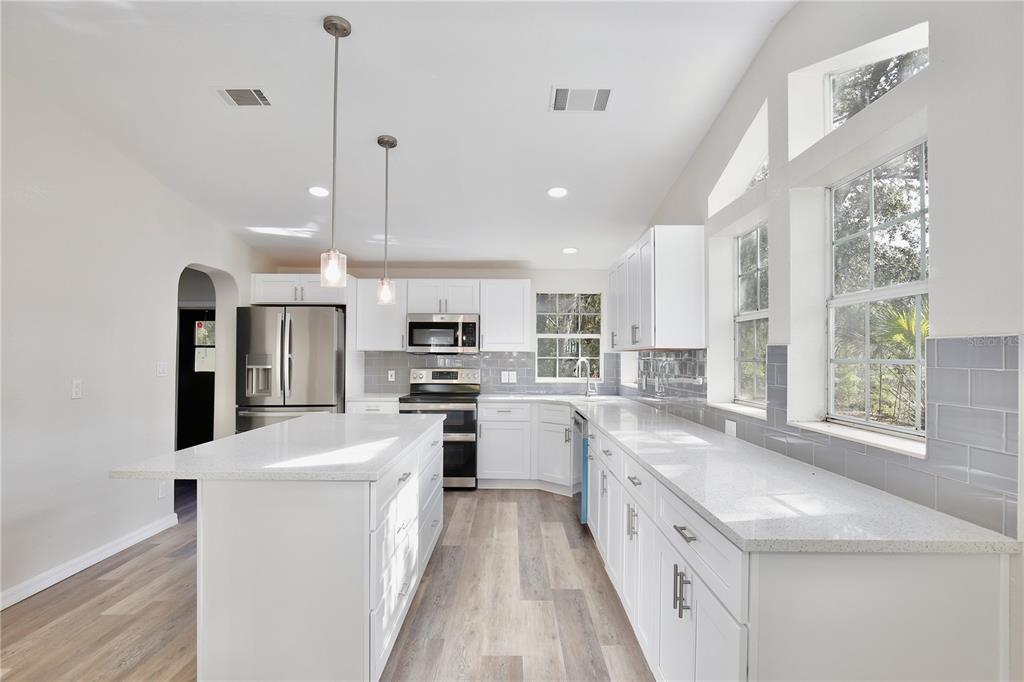 15330 Apache Pass Eustis, FL 32726 - Photo 14 of 44 a kitchen with stainless steel appliances kitchen island granite countertop a sink a stove a refrigerator cabinets and a large window