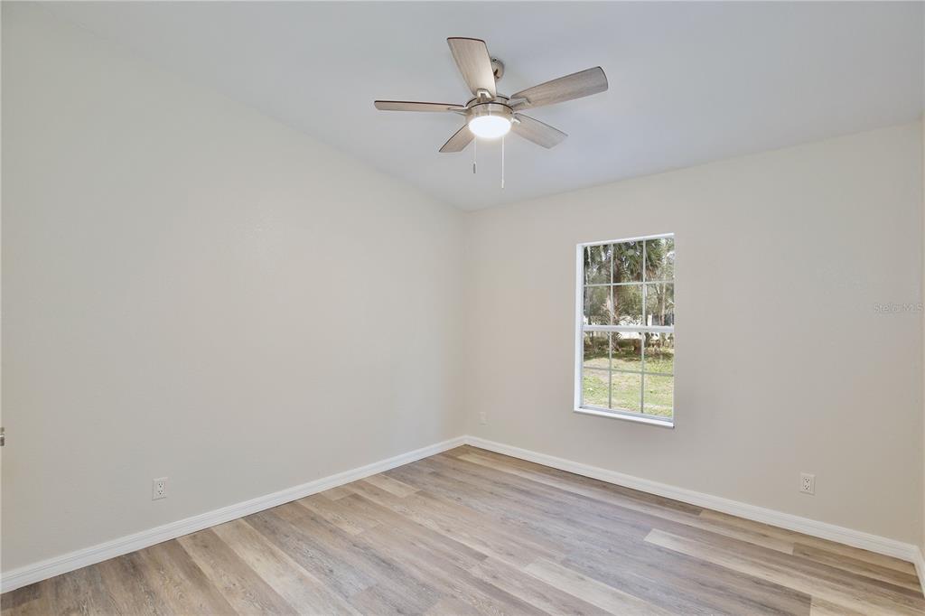 15330 Apache Pass Eustis, FL 32726 - Photo 24 of 44 an empty room with wooden floor ceiling fan and windows