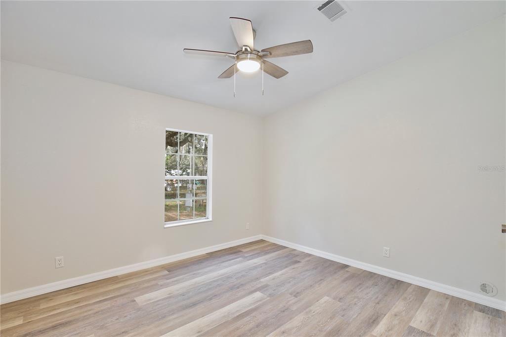 15330 Apache Pass Eustis, FL 32726 - Photo 27 of 44 an empty room with wooden floor ceiling fan and windows