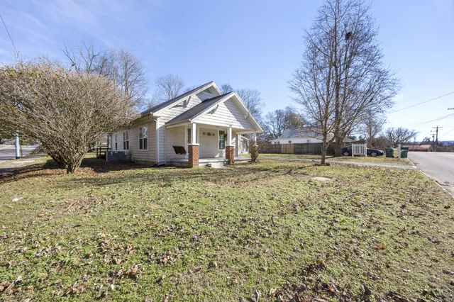 a front view of a house with a yard covered with snow and trees